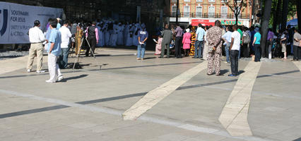 African, afrocarribean, back, bright, crowd, day, direct sunlight, England, eye level view, London, people, spring, square, standing, sunny, The United Kingdom