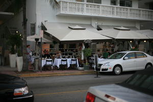 building, cafe, canopy, car, chair, dusk, eye level view, Florida, Miami, object, people, potted plant, sitting, standing, street, summer, table, The United States, winter