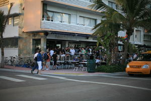 balcony, building, cafe, chair, couple, crossing, crowd, dusk, eye level view, facade, Florida, Miami, object, palm, people, sitting, standing, street, table, taxi, The United States, transport, tree, vegetation, walking, winter