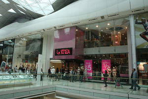 day, England, eye level view, group, indoor lighting, interior, London, mall, natural light, people, retail, shop, shopping, shopping centre, sign, The United Kingdom, walking