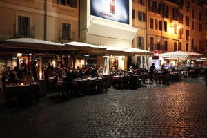 artificial lighting, eating, eye level view, furniture, group, Italia , Lazio, night, outdoor lighting, pavement, people, restaurant, Rome, sitting, street, summer, umbrella