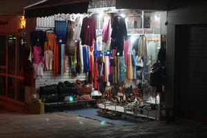 Agadir, artificial lighting, autumn, clothing, evening, eye level view, market, Morocco, object, souvenir, stall