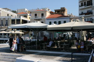 Agios Nikolaos, autumn, cafe, chair, day, eye level view, furniture, Greece, group, Lasithi, object, parasol, people, restaurant, sitting, standing, table