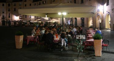 artificial lighting, cafe, chair, eating, eye level view, furniture, group, Italia , Lucca, night, outdoor lighting, outdoors, people, potted plant, sitting, square, summer, Toscana, umbrella