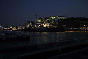 battleship, building, city, city, city lights, cityscape, dusk, England, evening, eye level view, London, river, riverbank, ship, spring, The United Kingdom, urban