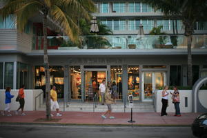 balcony, balustrade, building, cafe, chair, crowd, dusk, eye level view, facade, Florida, Miami, motorcycle, object, palm, pavement, people, sitting, standing, street, table, The United States, transport, tree, vegetation, winter