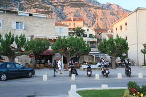 bollard, building, cafe, Croatia, dusk, evening, eye level view, Makarska, man, people, scooter, Splitsko-Dalmatinska, street, tree, vegetation, walking