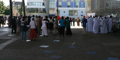 African, afrocarribean, back, bright, crowd, day, England, eye level view, London, nun, people, shady, spring, standing, sunny, The United Kingdom