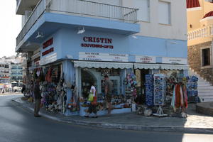 Agios Nikolaos, autumn, bag, clothing, couple, day, eye level view, Greece, jewellery, Lasithi, man, object, people, retail, sign, souvenir, standing, street