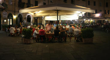 artificial lighting, cafe, chair, eating, eye level view, furniture, group, Italia , Lucca, night, outdoor lighting, outdoors, people, potted plant, sitting, square, summer, Toscana, umbrella