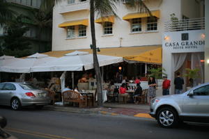 building, cafe, canopy, car, chair, crowd, dusk, eye level view, facade, Florida, Miami, object, people, sitting, standing, street, summer, table, The United States, winter