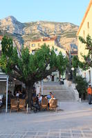 cafe, chair, Croatia, day, dusk, eye level view, family, furniture, group, Makarska, people, sitting, Splitsko-Dalmatinska, square, steps, table, tree, vegetation