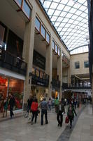 afternoon, artificial lighting, Cambridge, ceiling, couple, day, England, eye level view, group, object, people, retail, shop, shopping, shopping centre, sign, spring, The United Kingdom