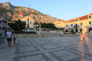 building, couple, Croatia, dusk, evening, eye level view, Makarska, pavement, people, plaza, Splitsko-Dalmatinska, standing, steps, tree, vegetation, walking, woman