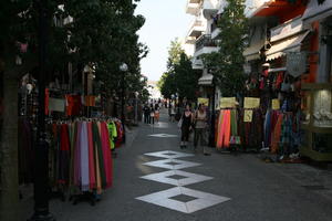 Agios Nikolaos, autumn, clothing, day, eye level view, Greece, group, Lasithi, object, people, retail, shopping, sign, souvenir, street, tree, vegetation