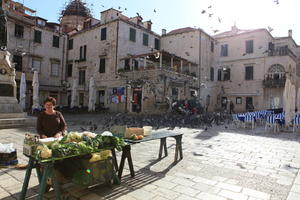 autumn, bird, bright, cafe, chair, Croatia, day, Dubrovacko-Neretvanska, Dubrovnik, eye level view, facade, furniture, house, natural light, pidgeons, square, stall, sunny, vegetables, vendor, woman